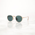 Gold round-frame sunglasses with tinted lenses on marble