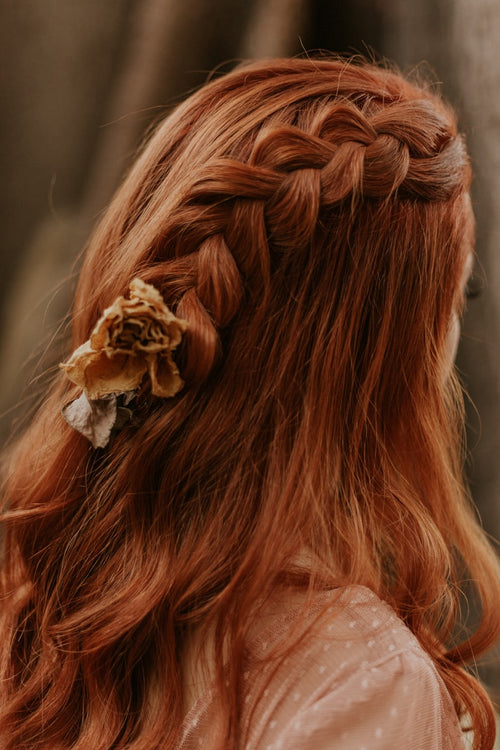 Auburn braided hair styled with a small flower hair accessory