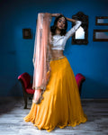 Woman wearing a yellow lehenga with silver blouse and pink dupatta