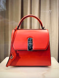 Coral structured top-handle handbag displayed on a stand