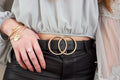 Black leather belt with gold double-ring buckle worn over an outfit