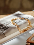 Chunky gold chain-link bracelet on an open book