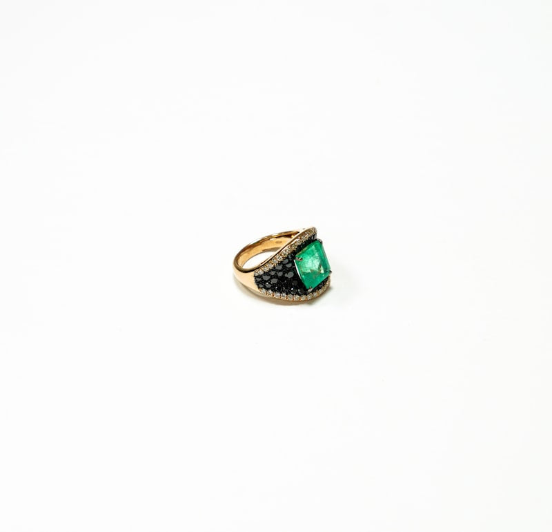 Emerald green cocktail ring in gold on white background