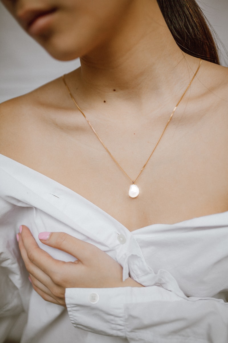 Single pearl pendant necklace worn on a model