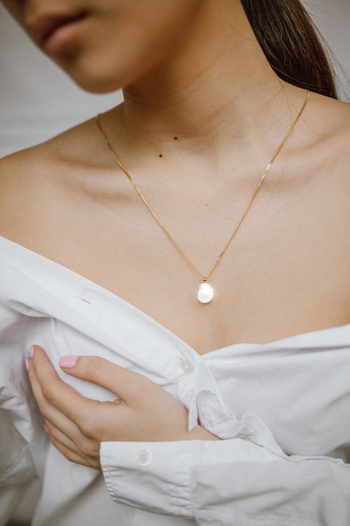 Single pearl pendant necklace worn on a model