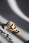 Twisted rope gold hoop earrings on a stone