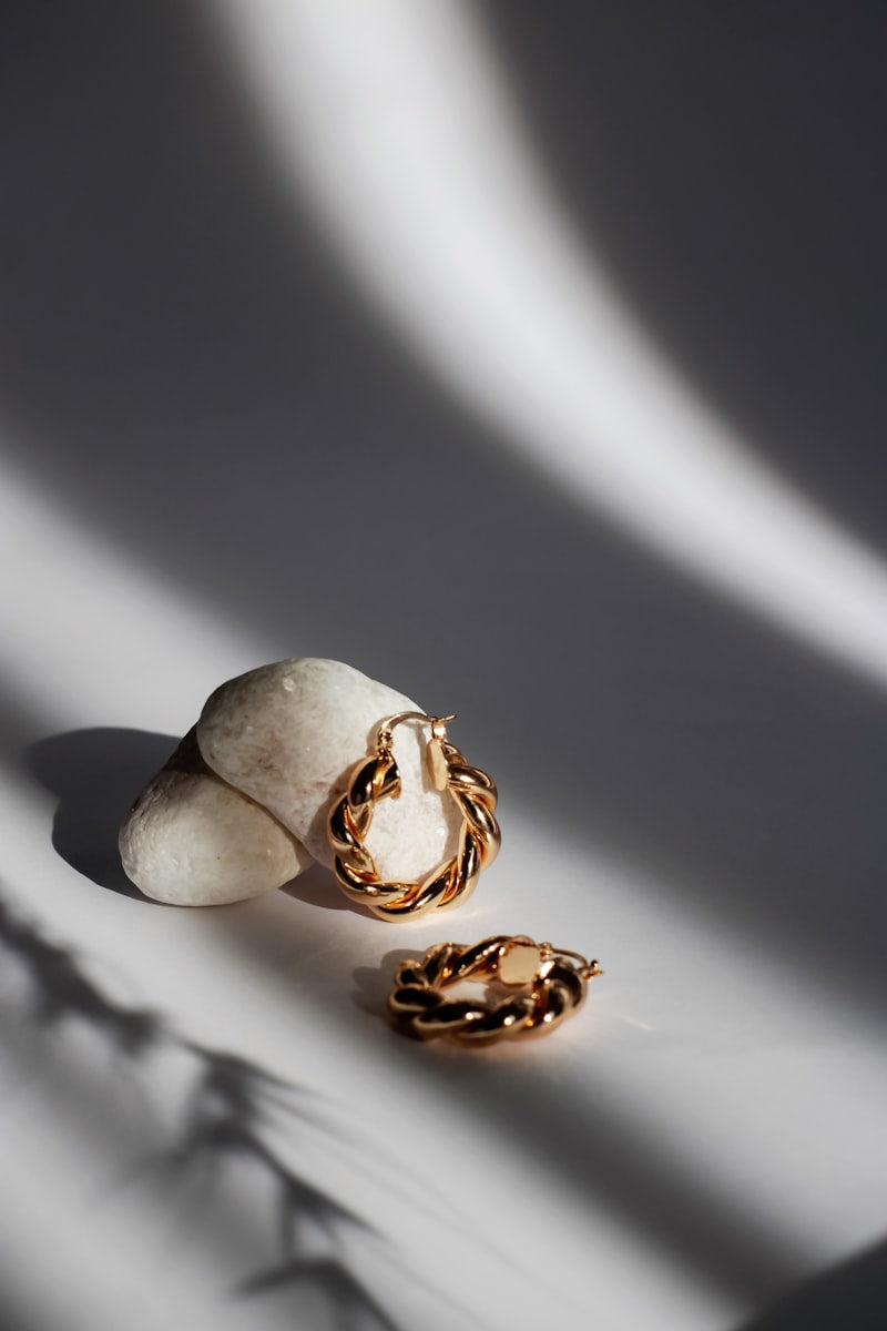 Twisted rope gold hoop earrings on a stone