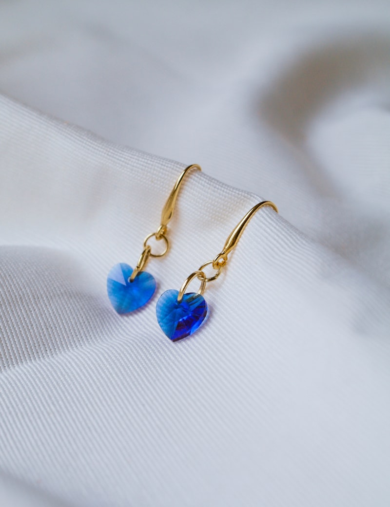 Blue crystal heart drop earrings on white fabric